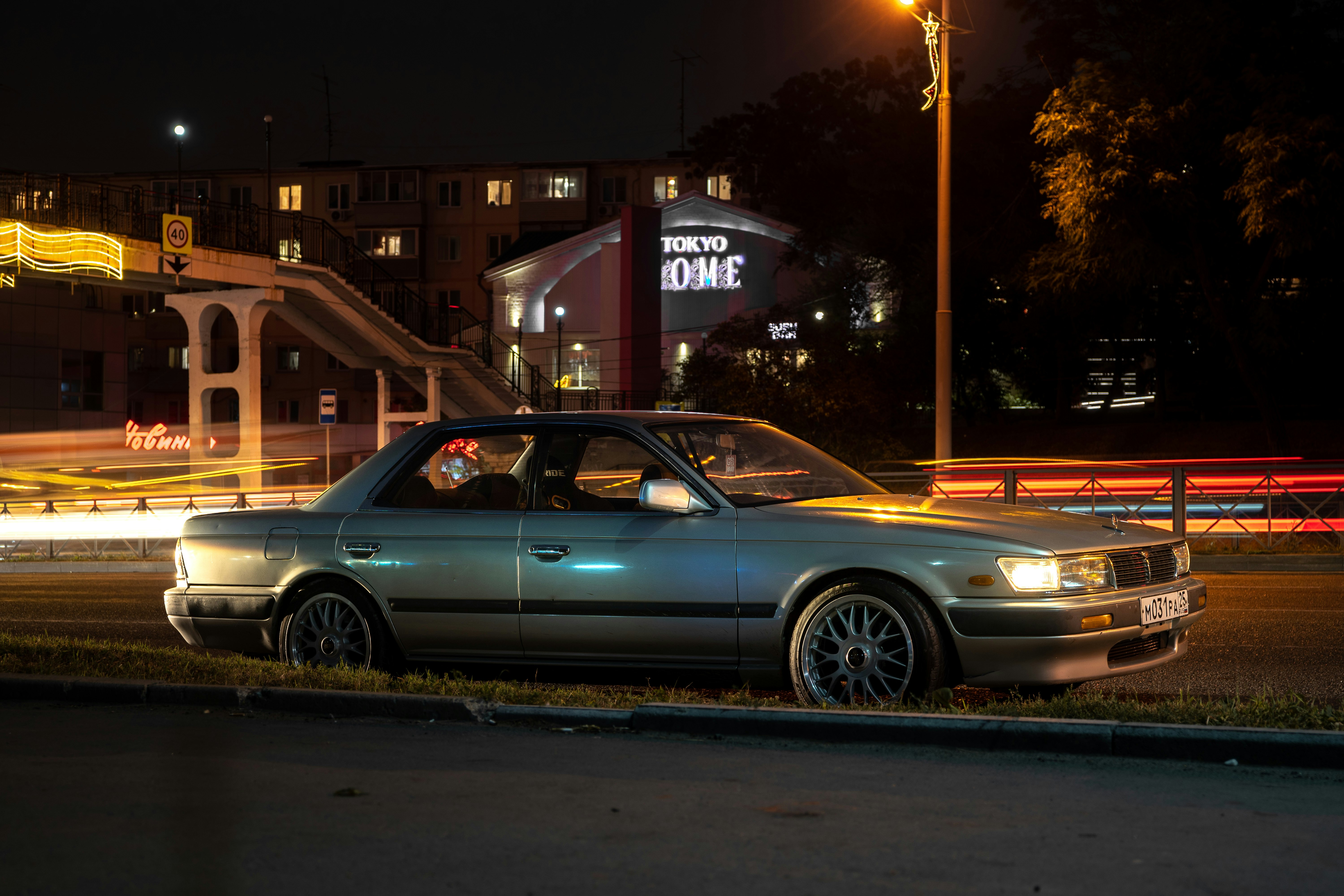 silver sedan parked beside the road during night time